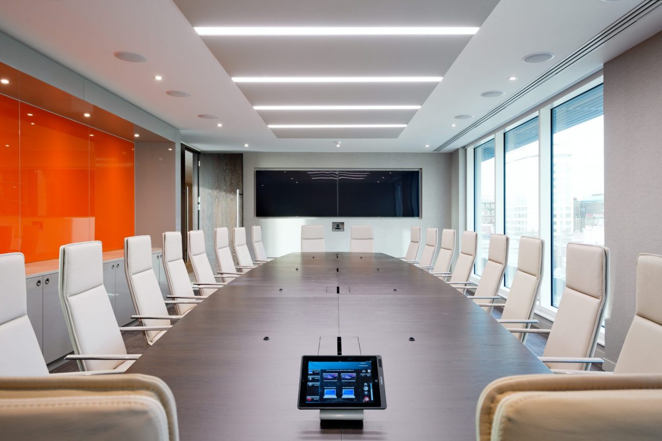 Modern 20 person boardroom with presenting screens and feature ceiling lighting.